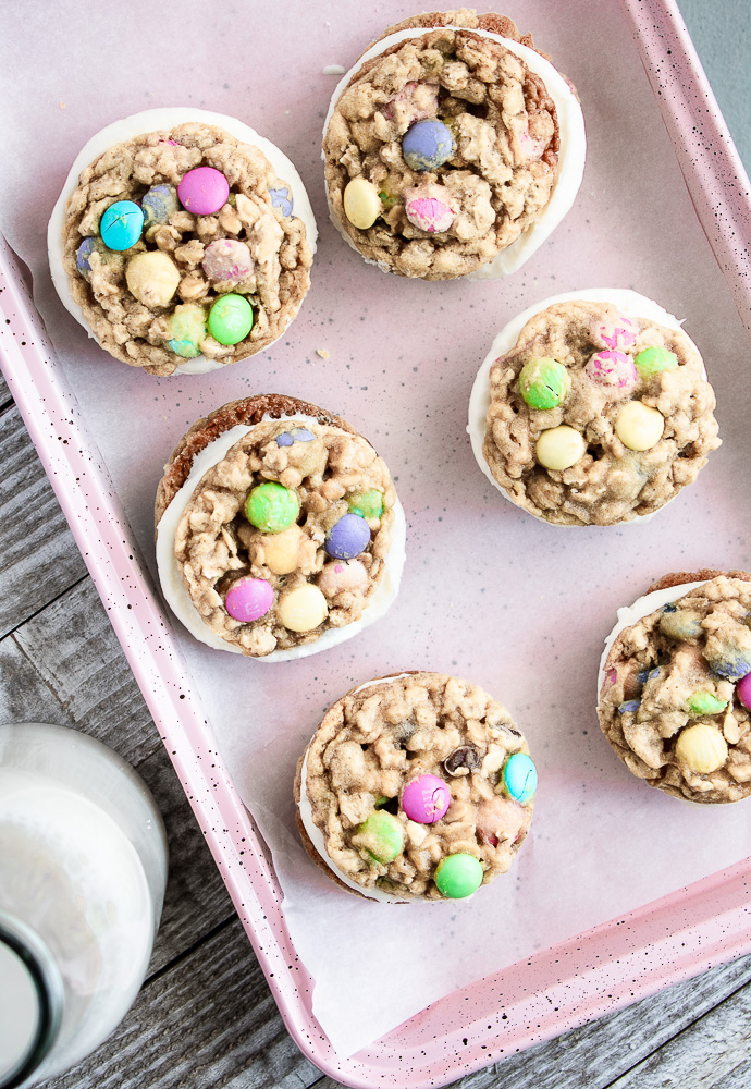 M&M Oatmeal Monster Cookie Sandwiches on a pink baking sheet.