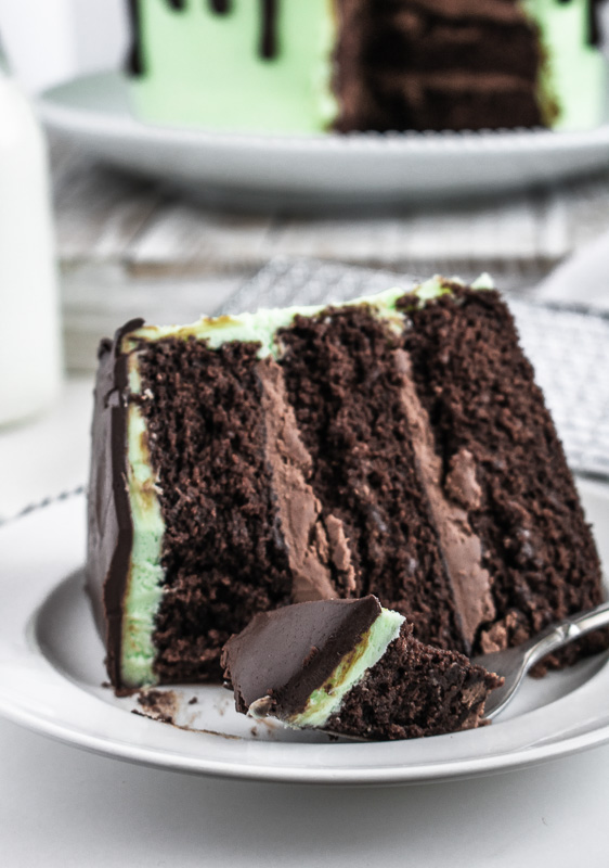 Slice of mint chocolate cake on a white plate with a bit on a fork
