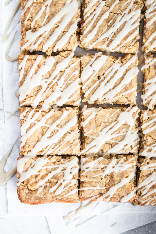 Slices of blondies on parchment paper with bourbon glaze drizzled on top