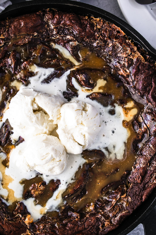 Vanilla bean ice cream on a skillet brownie in a cast iron pan
