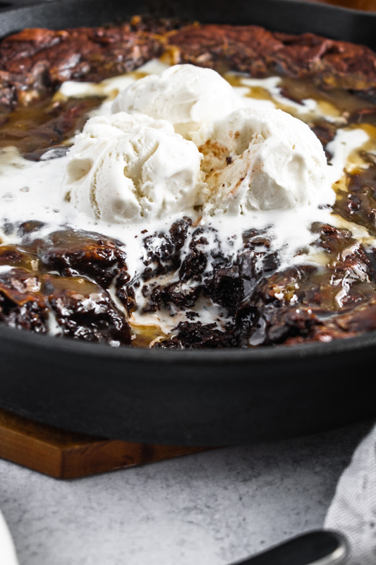 Vanilla bean ice cream melting on a warm salted caramel skillet brownie