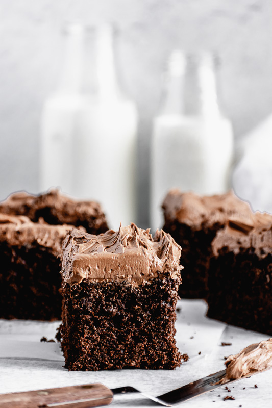 A thick slice of dark chocolate snack cake with dark chocolate buttercream on top