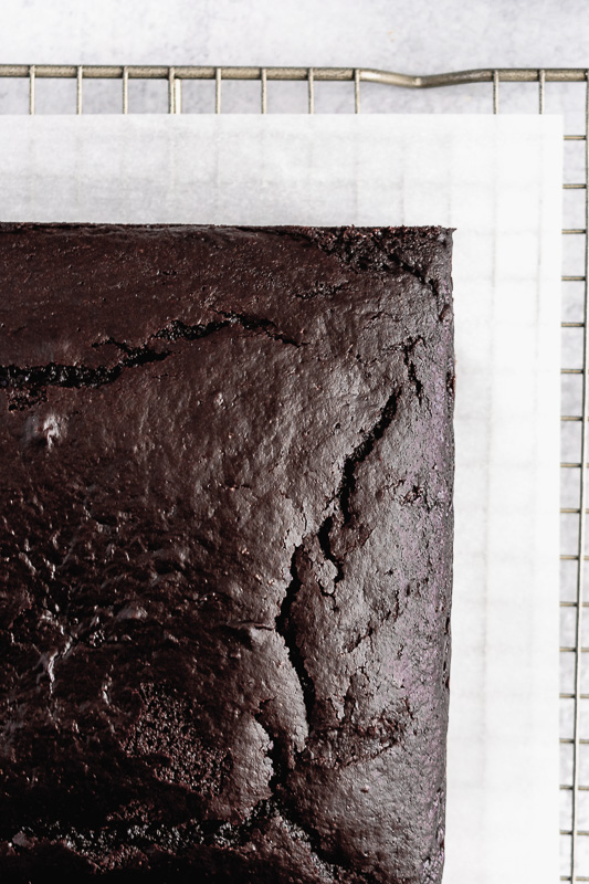 Unfrosted dark chocolate snack cake on a wire cooling rack