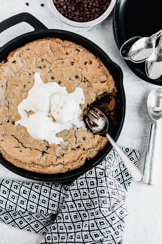 Brown butter chocolate chip skillet cookie with vanilla bean ice cream scoops on top