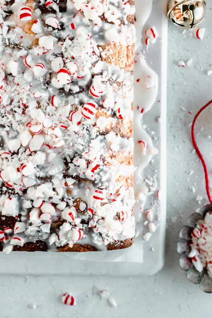 Cream cheese glaze and peppermint candies on top of peppermint marble loaf cake