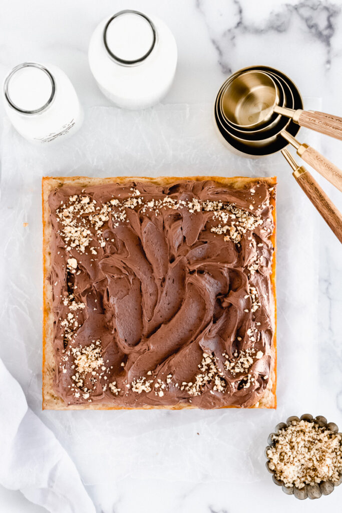 Banana snack cake with dark chocolate buttercream and pecans sprinkled on top