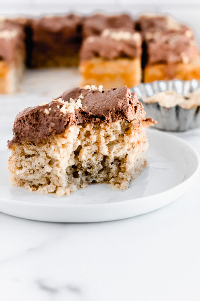 Slice of banana snack cake on a white plate with bite taken out