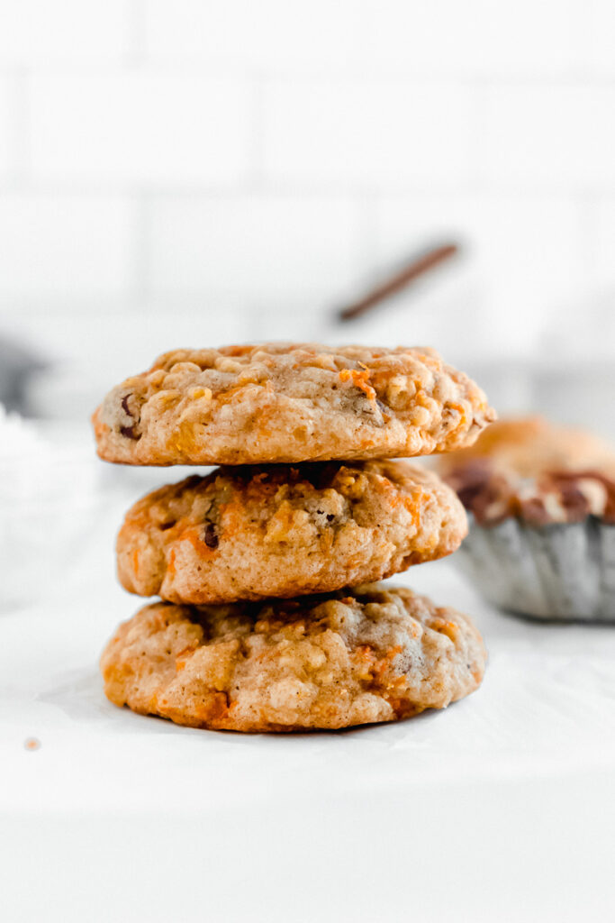 A stack of chewy carrot cake cookies on parchment paper