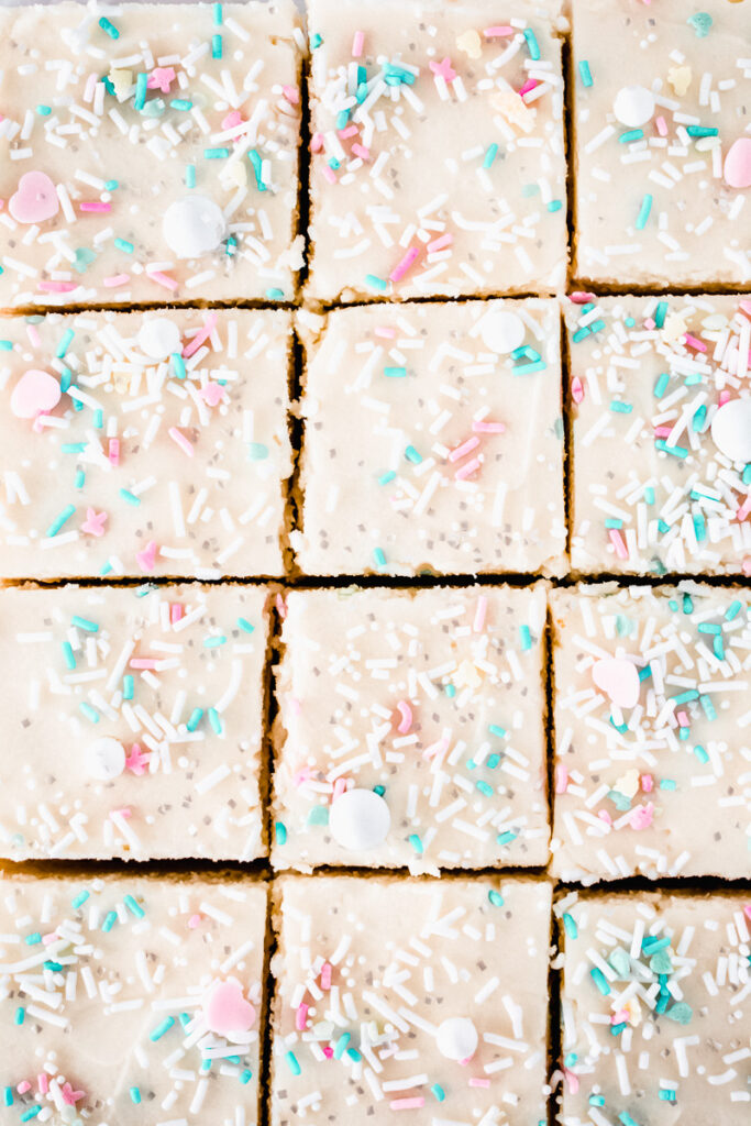 Lemon sugar cookie bars cut into squares and topped with vanilla cream cheese frosting and spring sprinkles