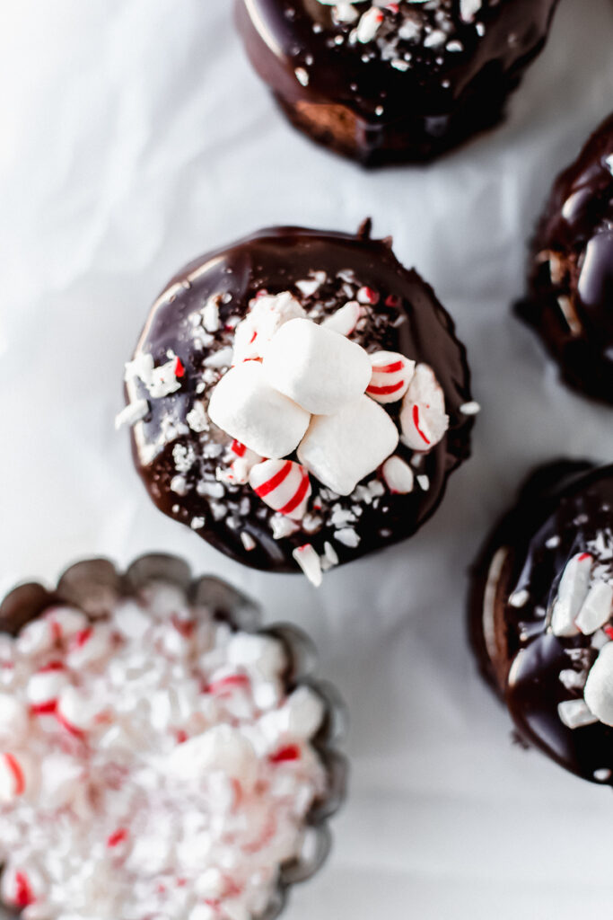 Top view of mini hot cocoa cakes topped with mini marshmallows, ganache, and crushed peppermint candies