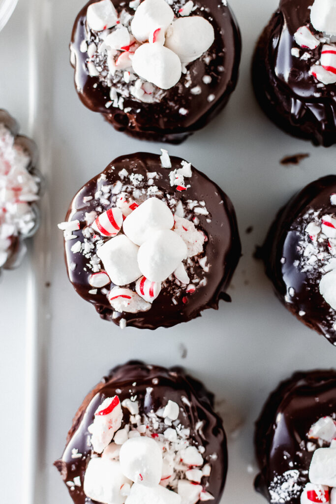 Top view of mini hot cocoa cakes topped with mini marshmallows, ganache, and crushed peppermint candies