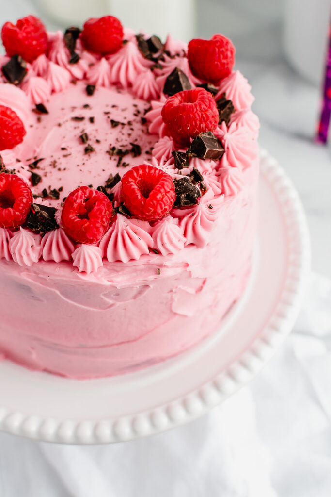 Raspberry chocolate layer cake on a white cake plate