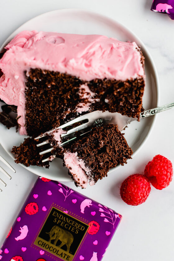 Slice of raspberry chocolate layer cake on a white plate with a fork